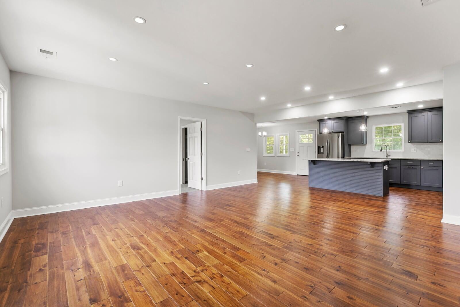 Open living area with wood floors and a kitchen beyond